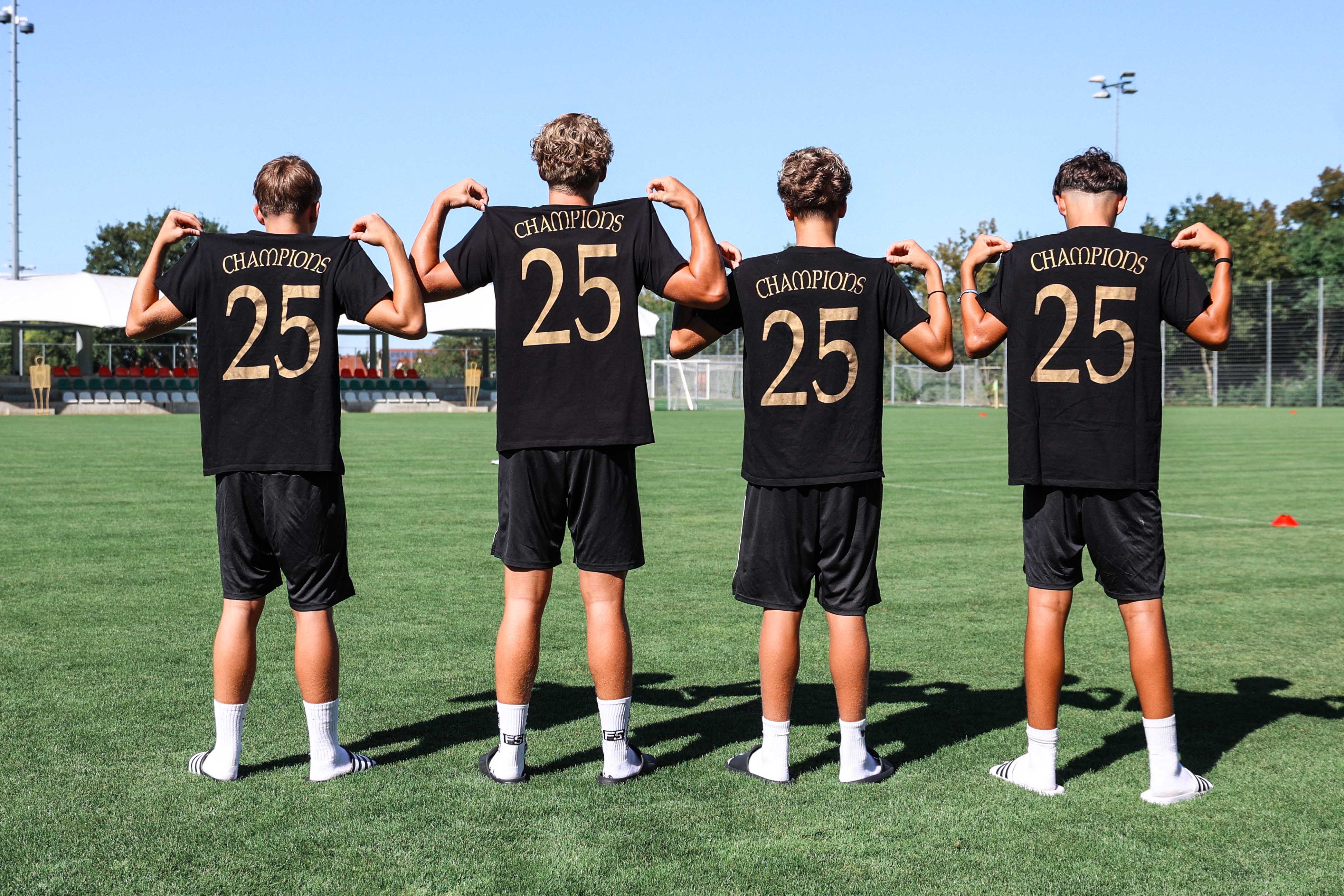 Vier Spieler des letztjährigen Turnierteams posieren mit ihren Champtions-T-Shirts.